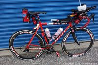 Full left-side view of red Aquila Giubilato Plus road bike showing frame, wheels, hydration system and saddle storage