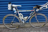Full side view of white and silver steel road bicycle leaning against blue door.