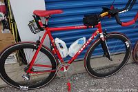 Full side view of the red bicycle showing frame, wheels, saddle and accessories