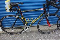 Full left-side view of bicycle showing Colnago frame, Easton fork, handlebars with aerobars, water bottles, saddle bag