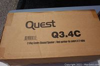 Cardboard box labeled 'Quest Q3.4C 2-Way Centre Channel Speaker' with shipping barcode, markings and tape sealing the box.