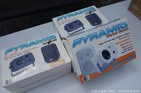 Three Pyramid speaker boxes on a table including Marine Series 3071-WP and Gold Series 3070 models, showing packaging and product images.