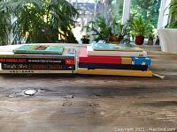 Books and journals stacked and displayed on wooden table showing size and cover details