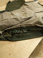 Ozark Trail branded double green air mattress laid out on a wooden surface showing the full length and branding.