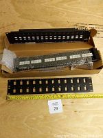 Two keystone patch panels and one new 48-port RJ45 punch down panel in box on wooden floor.