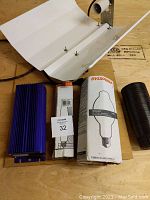 Lot laid out showing Lumatek electronic ballast, two boxed grow light bulbs (Sylvania and Son Agro), white metal reflector, and black hydroponic pots.