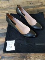 Pair of black almond toe dress shoes by Hugo Boss on black cloth shoe bag, showing overall condition and style.