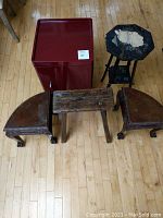 Photo showing the entire lot: red Ikea end table, two claw foot stools, rustic small plant stand, black octagonal plant stand, and small black stand