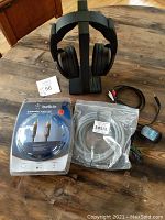 Sony MDR-RF985 wireless headphones on charging stand with cables and packaged subwoofer and Toslink cables on wooden surface