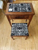 Top view of the vintage wooden sewing table with black and white fabric panel on top, matching upholstered chair with same fabric pattern.