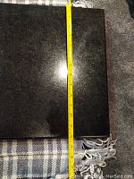 Black polished stone shelf with measuring tape showing width of approximately 14.25 inches.