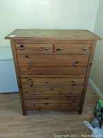 Front view of a 6 drawer wooden dresser chest showing scratches and natural wood grain finish.