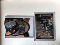 Two hockey cards of Mats Sundin in protective cases, one showing Sundin in action, one showing front and back of another card.