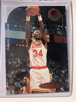 Front of Hakeem Olajuwon basketball card with action shot inside protective plastic sleeve.