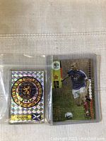 Front view of Zinedine Zidane soccer card and Angers Football Club holographic magnet in protective sleeves.