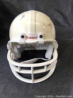 Front view of plain white miniature Riddell helmet with visible signatures near the top.
