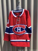 Front view of red Montreal Canadiens hockey jersey with large logo and number 13 on sleeve.