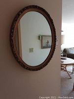 Front view of oval mirror hanging on wall showing entire reflective surface and frame