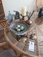 Image showing lot items on glass table including copper bowl with stone eggs, metal fish sculptures, diffuser, candleholder, and photo holders