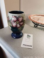 Front view of Moorcroft vase showing pink clematis flower design and footed base.
