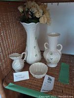 Photo of all four items together: tall vase with yellow flowers, medium vase, small bowl, and jug all with clover design and white porcelain.
