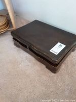 Closed dark wooden chest sitting on carpet.