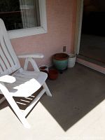 White plastic folding chair on patio with outdoor pots around it, showing full lot contents.
