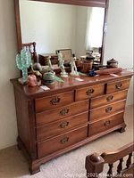 Full view of solid wood dresser with items on top and mirror behind