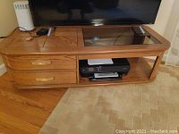 Full frontal view of coffee table showing glass top, two side drawers, and lower shelving with printer inside.