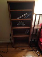 Front view of wooden bookcase with five shelves showing some books and items on shelves, wood is dark brown and worn