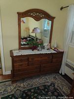 Full front view of solid wood dresser with attached ornate mirror, seven drawers, and visible scratches on top surface.
