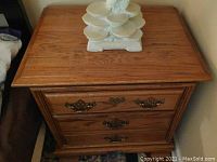 Top front view of the solid wood night stand showing wood grain surface, two drawers with ornate metal handles.