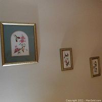 Three gold accent framed bird wall art pieces on wall, one large and two small.