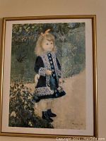 Renoir print showing young girl in blue dress with white lace, framed.