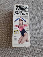 Front view of original Thigh Master box showing woman holding blue and white device