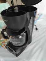 Mr. Coffee coffee maker with lid open, showing filter basket and glass carafe.