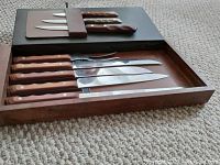 Photo of wooden-handled knives and sharpening steel in a wooden tray with slots for each item.