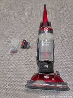 Front view of Hoover Wind Tunnel vacuum cleaner with two small attachment tools on carpet