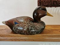 Side profile view of the hand-carved wooden duck decoy on display