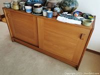 Full view of teak-veneer buffet with assorted pottery on top