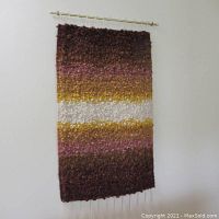 Full view of the vintage large Mid-Century Modern style wall hanging showing horizontal color bands and brass rod at top.
