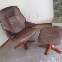 Chair and ottoman together in room corner near fireplace.