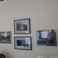 Three framed landscape photos on wall, featuring waterfalls and one mountain scene, in black and silver frames