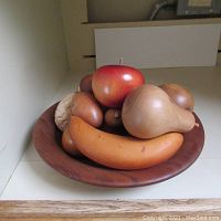 Photo showing the wooden fruit set in the bowl including banana, pear, apple and smaller round fruits.