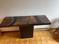 Full view of the rectangular vintage hall table with stone tile top and solid stone base against a wall.