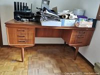 Front view of retro MCM double pedestal desk with office supplies on top