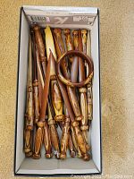 Box of handcrafted wooden letter openers and one wooden bangle, showcasing overall contents of the lot.
