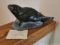 Side view of carved seal sculpture on base showing overall shape and surface wear