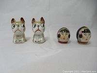 Front view of two sets of salt and pepper shakers including two dog-shaped and two Asian woman head-shaped shakers.