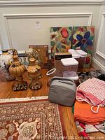 Decorative ceramic urns, kitchen wall art, plastic storage containers, and folded aprons or linens on floor